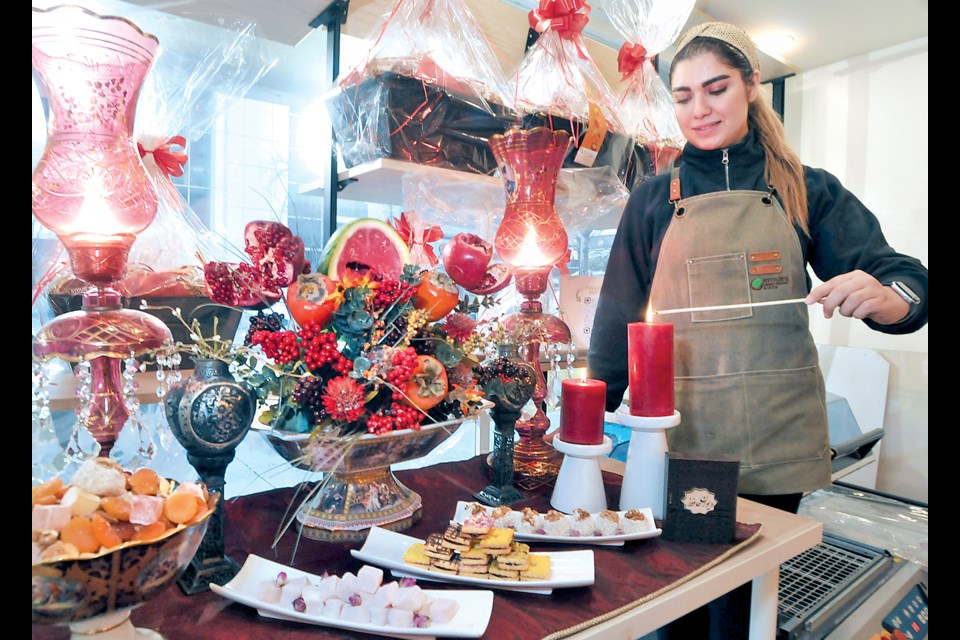 Ayoub's Dried Fruits and Nuts staff member Saba Mirzadeh tends to the Yalda Night table she created to celebrate the Winter Solstice. | Paul McGrath / North Shore News